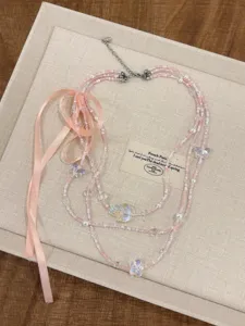 Collana di perle multistrato stile balletto con nastro rosa e ciondolo farfalla in cristallo.