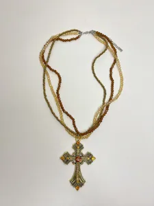 Gros plan sur le collier de perles multicouche avec pendentif croix orné rétro.