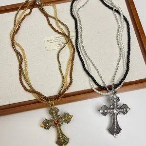 Collier ras de cou multi-couches en perles avec pendentif croix style cool pour femmes.