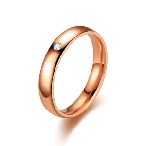 Primo piano di un anello minimalista in oro rosa con singola pietra e fascia lucida.