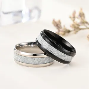 Détail de bague de couple texturée en acier inoxydable, design à double biseau argent et noir.