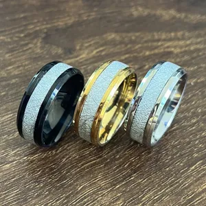 Détail de bague en acier inoxydable avec un motif texturé unique et des bords biseautés.