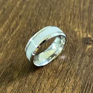 Détail de bague en acier inoxydable avec texture givrée et bords biseautés polis.