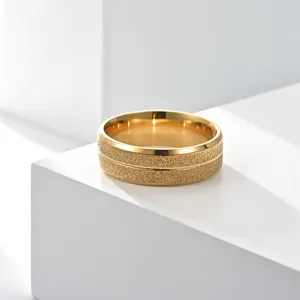 Bague en acier inoxydable doré avec texture mate et rainure centrale gros plan.
