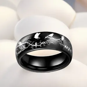 Gros plan de la bague en acier noir gravée avec des motifs d'oiseaux et de branches d'arbres.