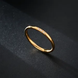 Gros plan détaillé d'un anneau minimaliste en acier plaqué or 18k avec trois petites pierres zircones.