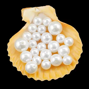 Close-up of white imitation pearl beads with holes inside a natural yellow seashell display.
