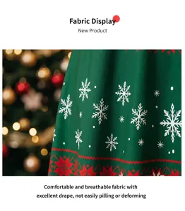 Détail du tissu de la robe de Noël, matière verte avec flocons blancs et motifs rouges.