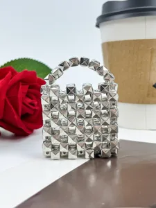 Vista detallada del mini colgante de bolso con tachuelas piramidales de metal plateado y llavero.