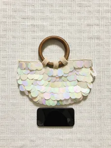 Iridescent sequin handbag detail view, featuring a round wooden handle and woven evening style.