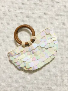 Detailed view of iridescent sequin evening handbag with wooden ring handle and sparkle finish.