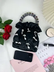 Détail de sac seau en satin noir avec poignée perlée et beaux pendentifs pour la mode.