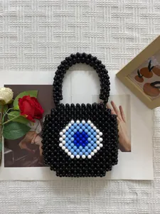 Handmade beaded evil eye handbag close up view, stylish black woven purse detail.