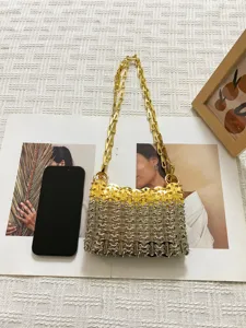 Primo piano dettagliato di una borsa a tracolla intrecciata in anelli metallici con catena.