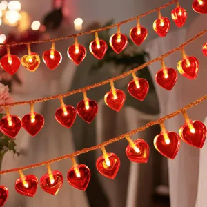 Detail view of red heart LED string lights, warm glowing romantic fairy lights for room decor.