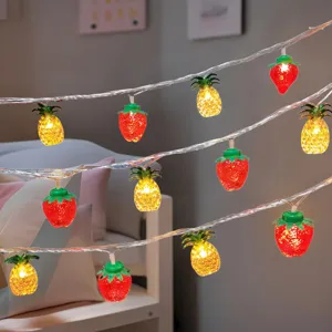 Close-up of glowing strawberry and pineapple LED string lights creating cozy indoor vibe.