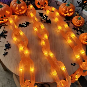 Detalle de cadena de luces Halloween LED, eslabones de plástico naranja con bombillas cálidas.