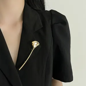 Exquisite smooth alloy brooch detail shot, elegant gold stem pin for women suits.