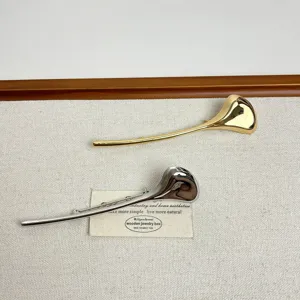 Detail shot of elegant gold and silver leaf branch brooches, smooth metal alloy design.