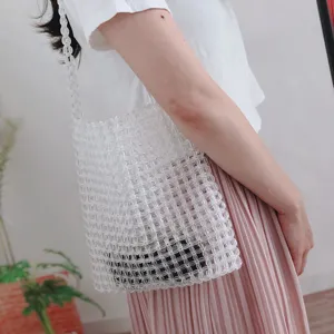 Dettaglio borsa a tracolla in perle acriliche trasparenti, design intrecciato a mano.
