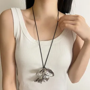 Detailansicht der ausgefallenen Metall Blumen Anhänger Kette mit langem schwarzen Lederband.