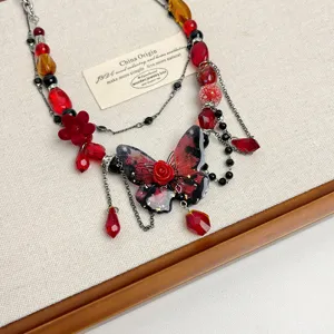 Primo piano della collana choker di perle con farfalla rossa, dettaglio gioielli punk.