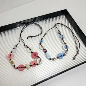 Handgemaakte knoop geweven ketting detail met kleurrijke bedels op een mooi dienblad.