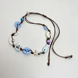 Handgemaakte blauwe knopenketting detail toont een schattige zeester en vishangers.