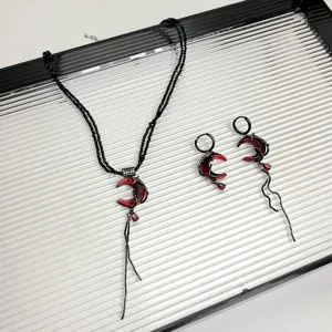 Detailaufnahme der gotischen roten Mondsichel Halskette und Ohrringe mit filigranem Design.