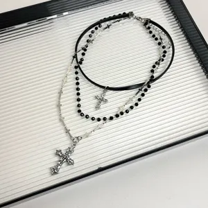 Dettaglio ravvicinato della collana girocollo gotica multistrato con perle nere e croci pendenti.