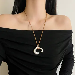 Long brown leather cord necklace with irregular silver U-shaped metal pendant for women.