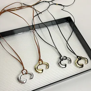 Minimalist long leather cord necklace with metallic U-shaped pendant for women daily wear.