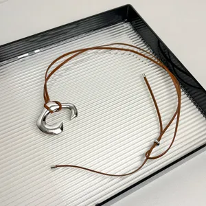 Long brown leather cord necklace featuring a stylish silver metallic C-shaped pendant for women.