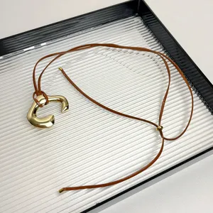 Detailed view of the chic metal pendant necklace with brown leather cord, minimalist design.