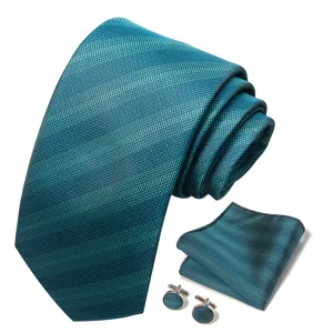 Gedetailleerd overzicht van de blauwgroene jacquard das, pochet en bijpassende manchetknopen.