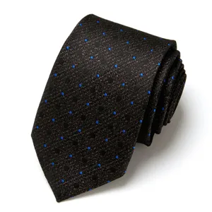 Close-up detail of dark mens jacquard tie featuring blue polka dots, rolled elegant style.
