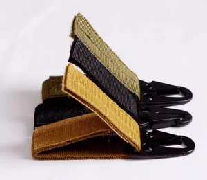 Detailed view of tactical webbing keychain and metal carabiner hook for outdoor gear.