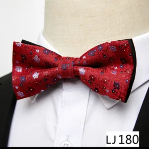 Gros plan détail d'un nœud papillon jacquard floral rouge sur un col de chemise blanc.