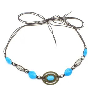 Detailed view of vintage bohemian hat band with blue stones, metal beads, and brown cord.