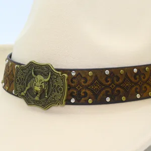 Close-up detail of western cowboy hat featuring bronze bull buckle and embossed leather band.