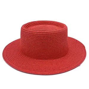 Detalle de sombrero de paja plano rojo, textura tejida fina para protección solar de verano.