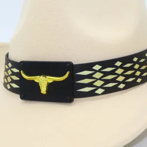 Detalle en primer plano del sombrero de vaquero occidental con correa negra y emblema de toro dorado.