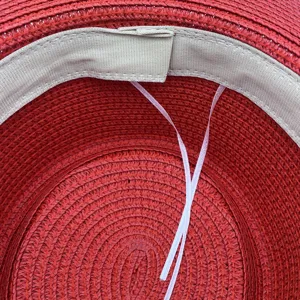 Vista detallada del interior del sombrero de paja rojo con banda de sudor beige y cuerda ajustable.