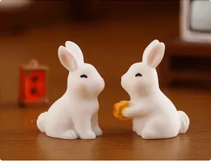 Gros plan détaillé de figurines de lapin en résine mignonnes tenant un gâteau de lune miniature.