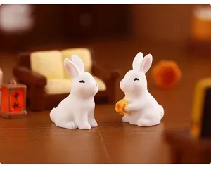 Gros plan de petites figurines de lapin en résine blanche, détail de décoration lune.