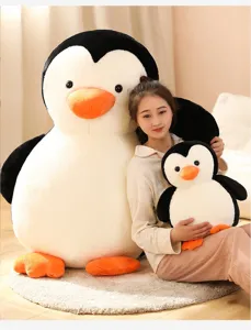 Primo piano del peluche di pinguino gigante e del simpatico compagno in un ambiente accogliente.