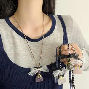 Close-up view of lace bow handbag pendant necklace featuring crystal stone and stylish braided cord.