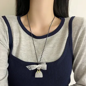 Detailed shot of a delicate lace bow necklace with a cute bag pendant on black and white cord