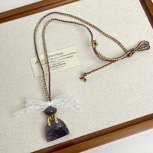 Niche design necklace featuring a purple crystal bag pendant and delicate white lace bow.