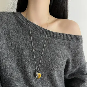 Close-up of the long silver chain necklace featuring a heart natural stone pendant and grape charm.